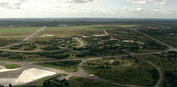 Et billede taget over en lille del af Flyvestation Karup som den ser ud i dag. Den hvide platform nederst i billedet er en del af den Civile lufthavn. I baggrunden ses startbanerne